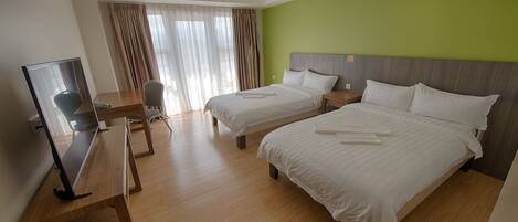 A hotel room with two beds, a desk with a chair, a television, and a window with curtains.