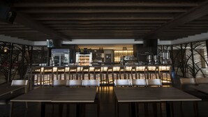 Een restaurant met een bar, houten plafond en een zithoek.