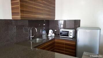 A kitchen with a stainless steel sink, a microwave, and a refrigerator.