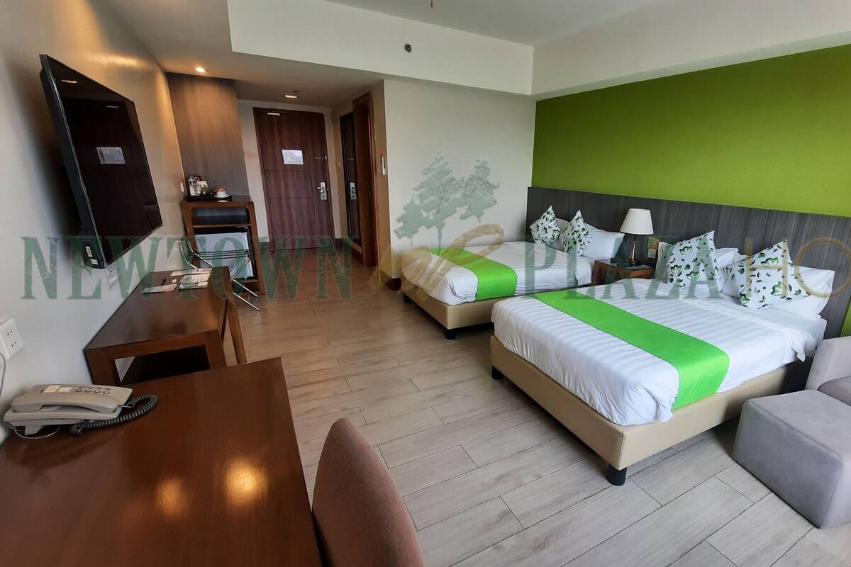 Een hotelkamer met twee bedden, een bank, een bureau en een televisie.