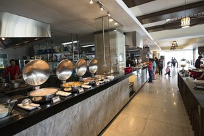 Ein Buffetbereich mit verschiedenen Speiseausgaben und einer Küche im Hintergrund.