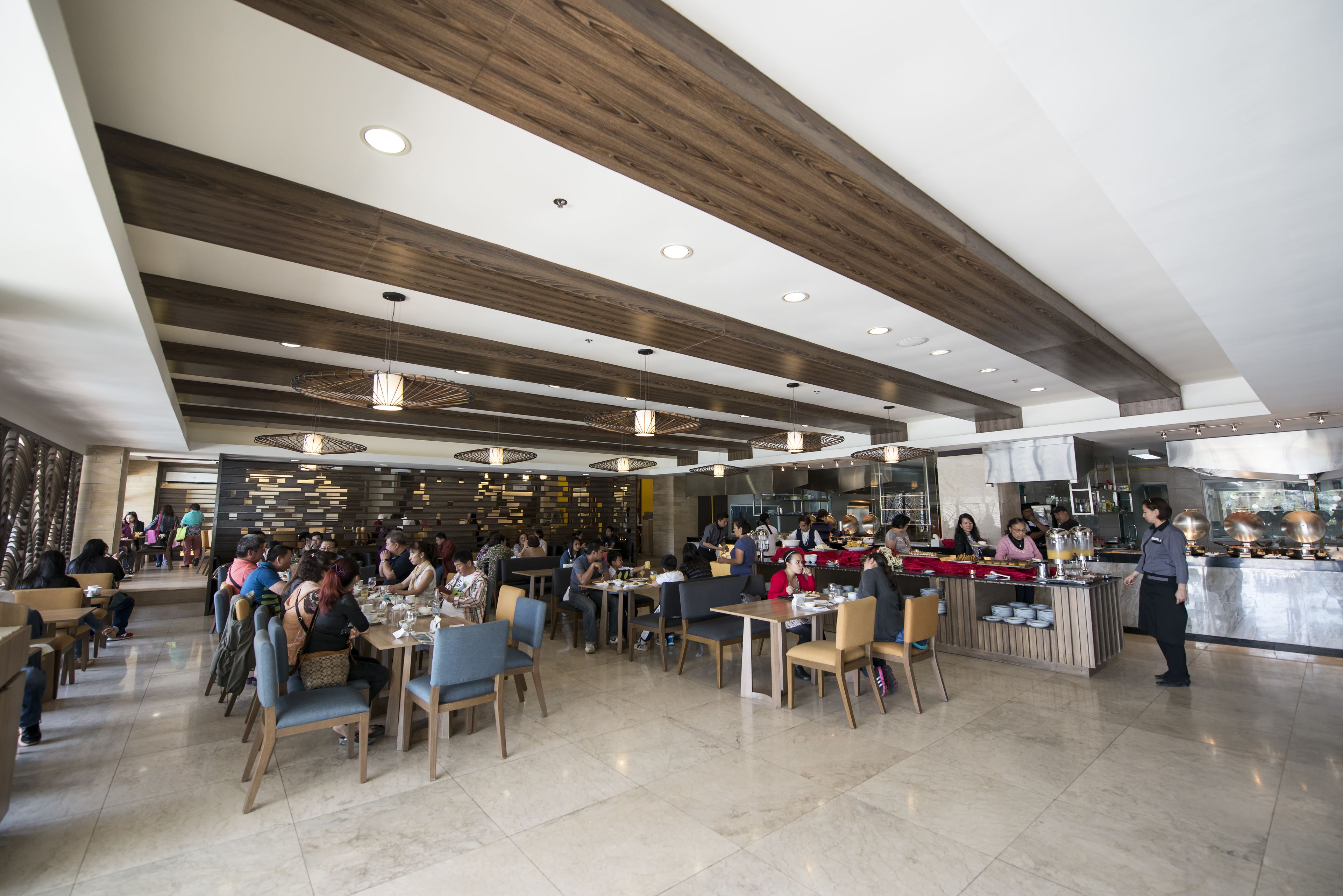 A spacious restaurant with high ceilings, wooden beams, and modern pendant lighting.