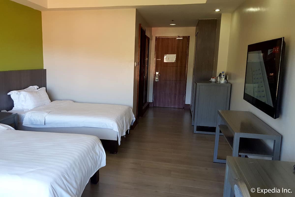 Een hotelkamer met twee bedden, een bureau, een televisie en een kast.