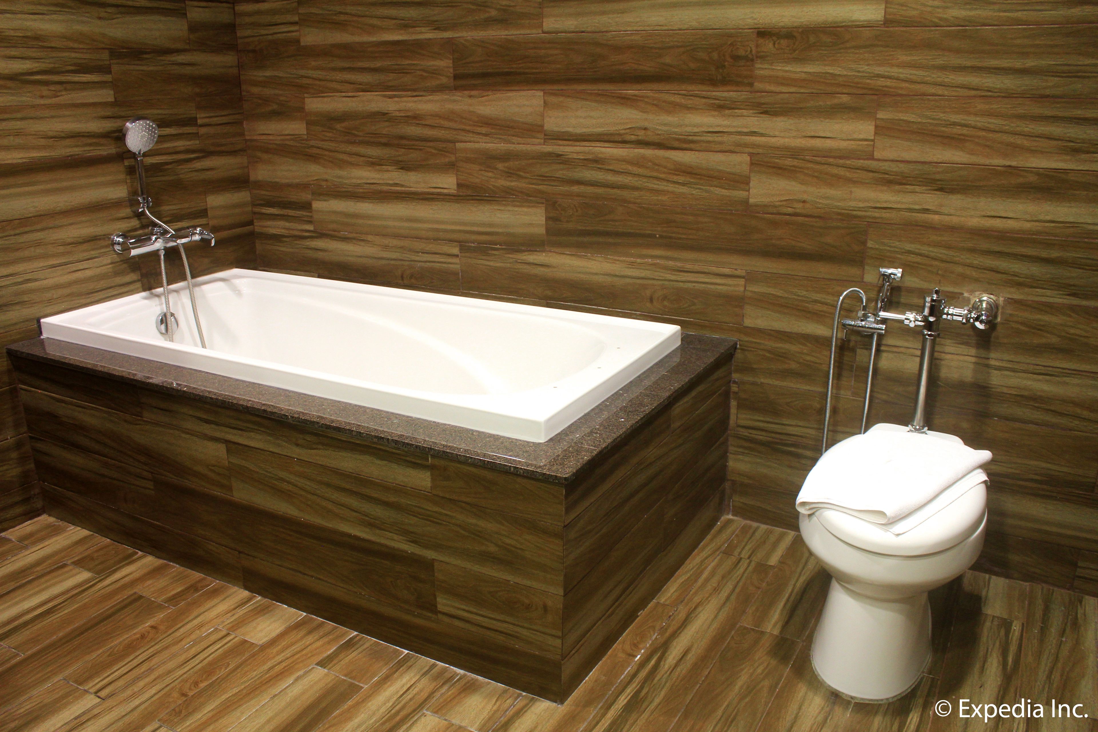 A modern bathroom with a freestanding bathtub, a toilet, and a showerhead.