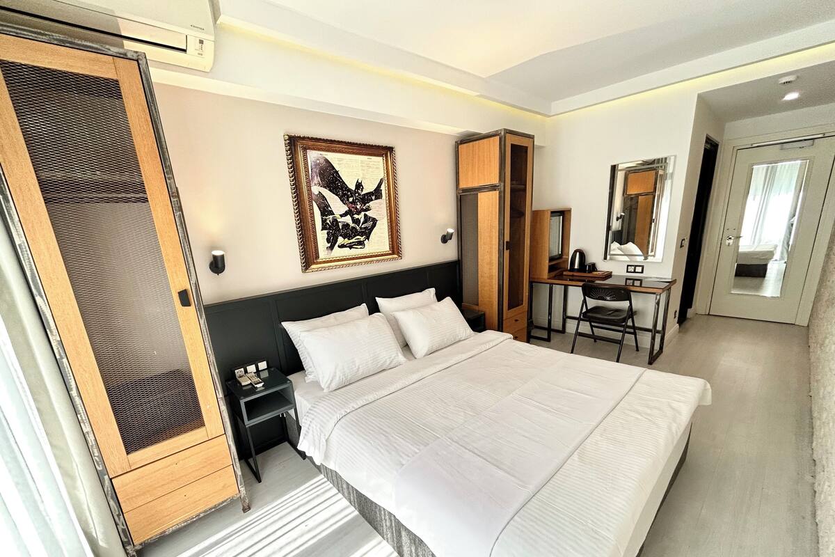 Una habitación de hotel moderna con una cama grande, un escritorio, una silla y un armario.