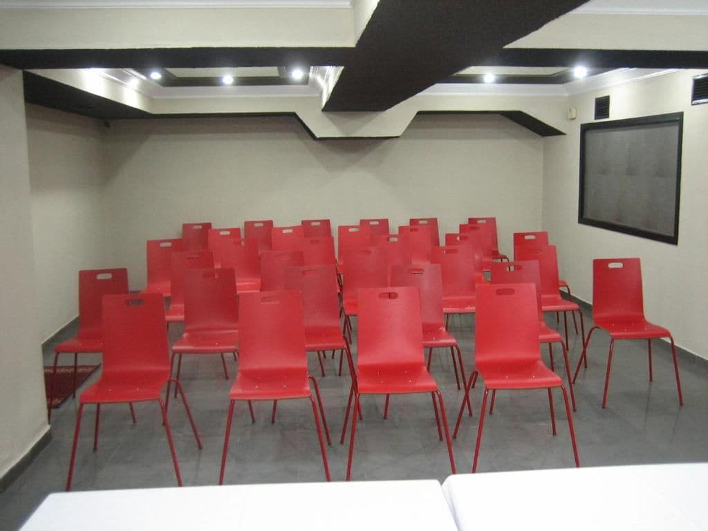 Ein Konferenzraum mit Reihen roter Stühle und einem weißen Tisch.