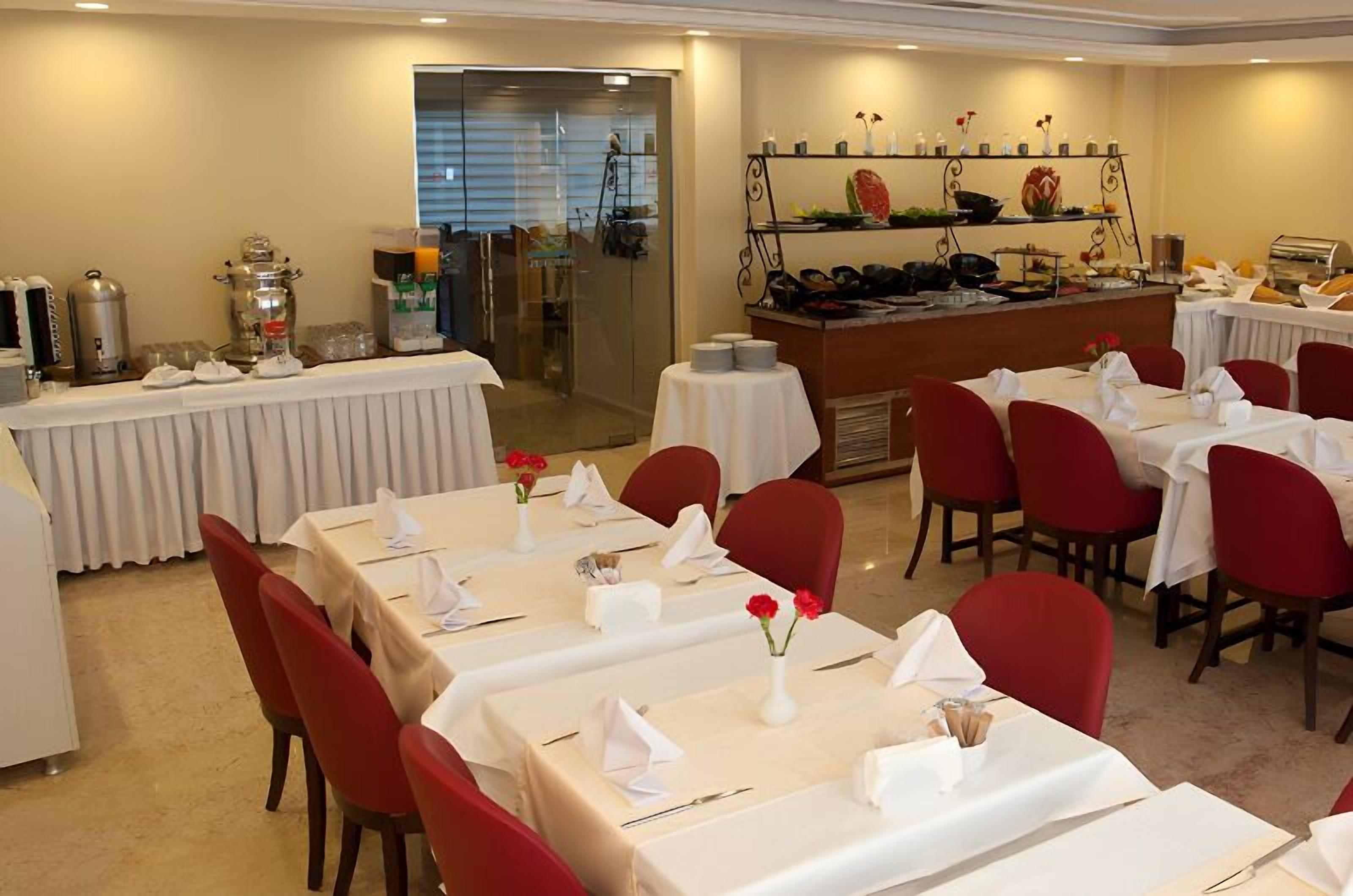 A dining area with tables set for service, a buffet counter, and a refrigerator.
