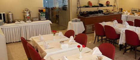 A dining area with tables set for service, a buffet counter, and a refrigerator.