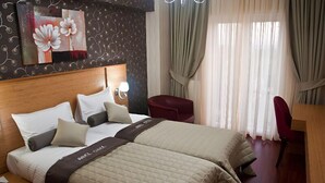 A hotel room with two beds, a wooden headboard, a red chair, a desk, and a large window with curtains. - Abel Hotel (Istanbul)
