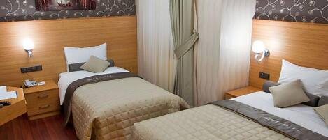 Quarto de hotel com duas camas, cabeceiras de madeira, mesa de cabeceira com abajur e um quadro na parede.