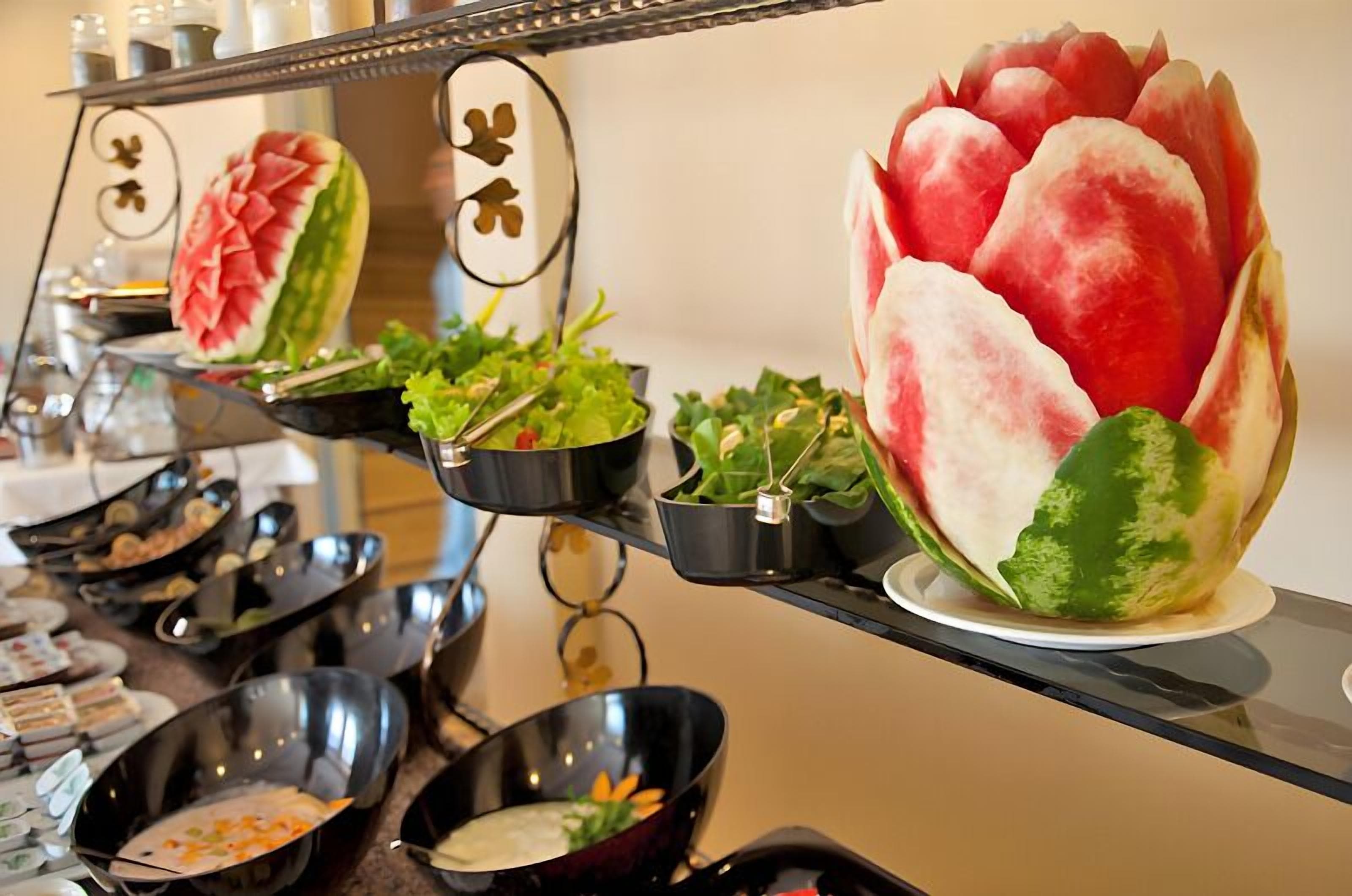A buffet with various dishes and a large decorative watermelon centerpiece.