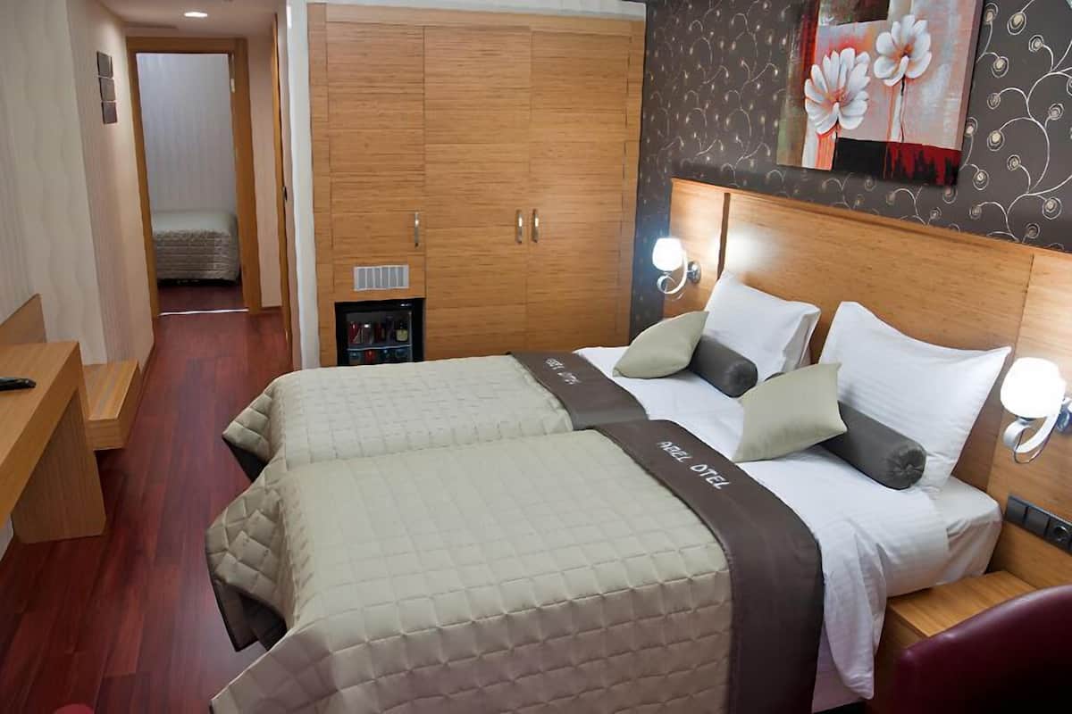 A hotel room with a large bed, wooden wardrobe, and a small seating area.