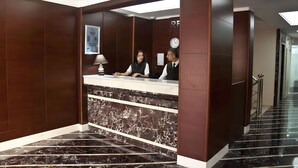 A reception area with a marble counter, wooden paneling, a clock, and a staircase leading to another floor. - Abel Hotel (Istanbul)