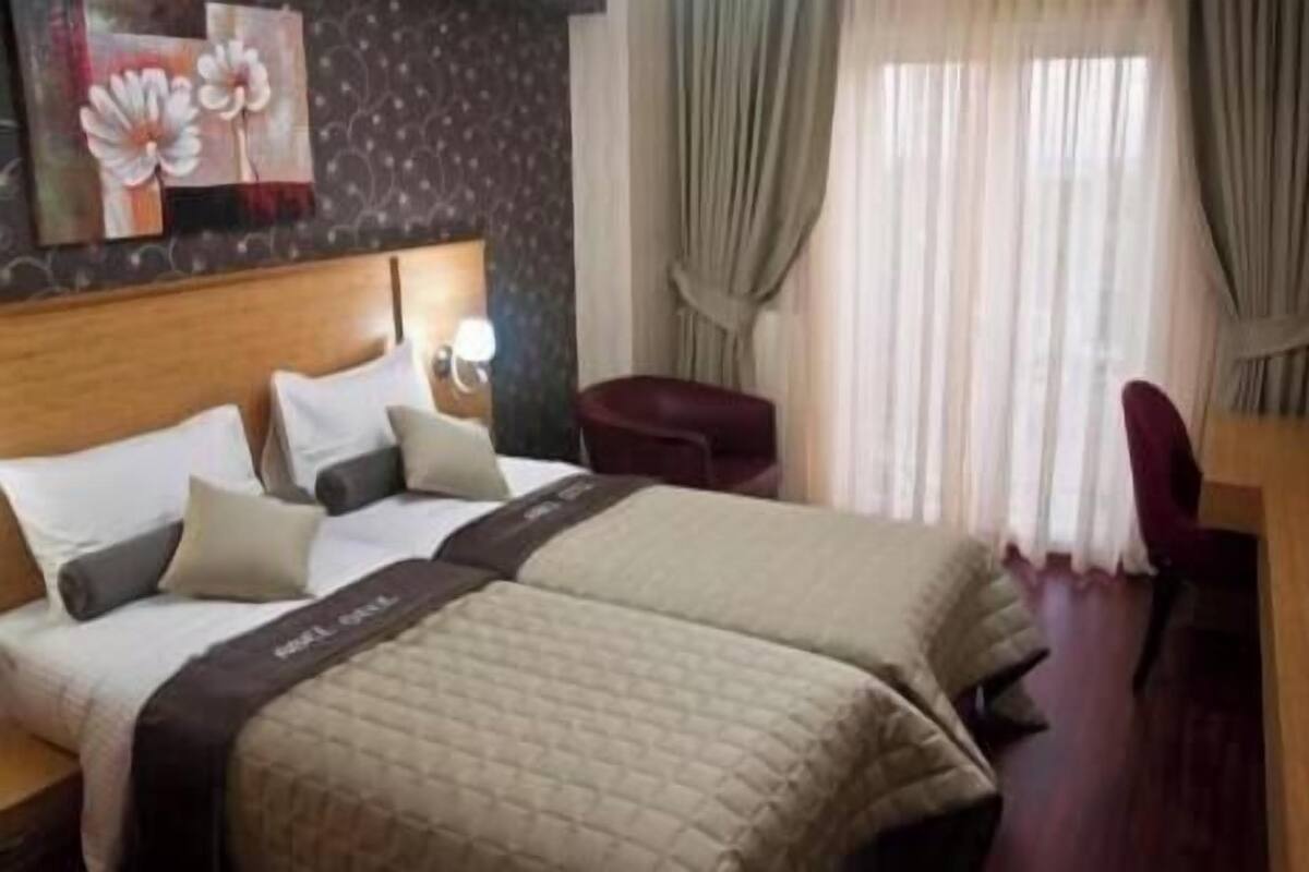 A hotel room with two beds, a desk, and a chair.