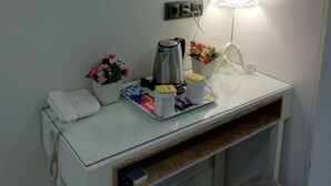 A hotel room with a white console table, a painting of a cityscape, a bedside lamp, a telephone, and a small plant. - Just Inn Hotel (Istanbul)