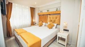 A hotel room with a large bed, a bedside table, a wall-mounted TV, and a window with curtains. - Just Inn Hotel (Istanbul)
