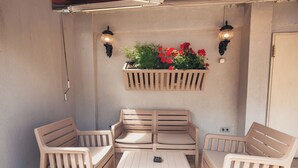 A patio with a wooden bench, a table, and a planter with flowers. - Just Inn Hotel (Istanbul)