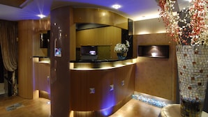 A reception area with a curved wooden reception desk, a flat-screen TV, and a decorative vase with flowers. - The Moon Hotel (Taipei)