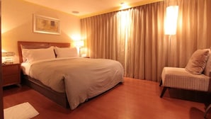A hotel room with a large bed, a chair, a nightstand, and a painting on the wall. - The Moon Hotel (Taipei)