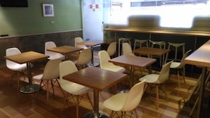 A dining area with multiple tables and chairs, a tiled floor, and a green wall with a framed picture. - The Moon Hotel (Taipei)
