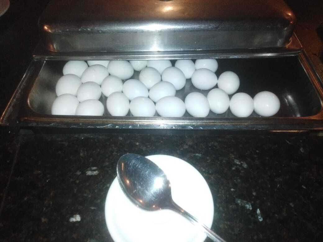 A tray of white spherical objects, possibly food items, on a countertop with a spoon beside them.