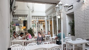 Un café avec des tables et des chaises blanches, un mur en briques et une fenêtre donnant sur la rue.