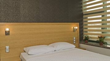 Un dormitorio moderno con una cama grande, cabecero de madera, lámparas de noche y una ventana con persianas.