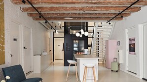 Et moderne interiør med blotlagte murstensvægge, en trappe, et køkkenområde og et siddeområde med en barstol.