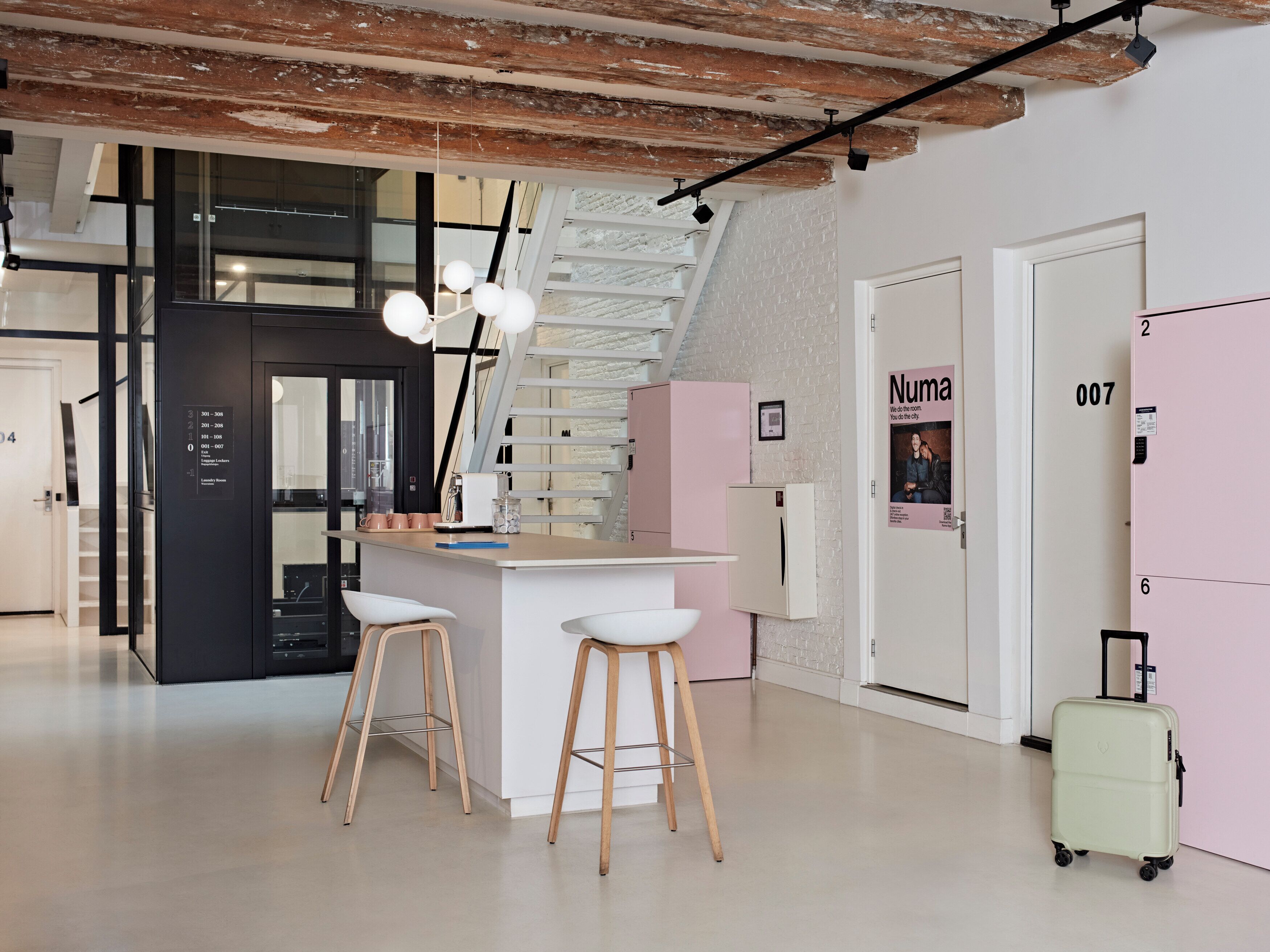 A modern kitchen with a bar area, a staircase, and a refrigerator with a QR code.