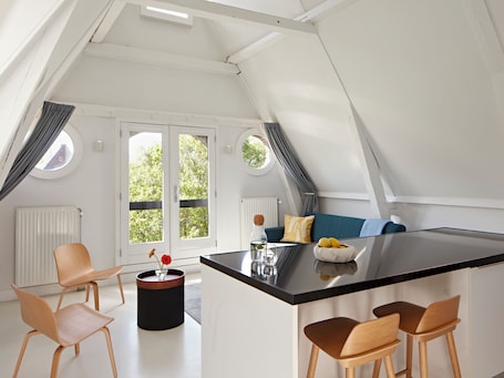 A modern kitchen with a central island, two round windows, and a view of greenery outside.. YAYS Amsterdam Salthouse Canal by Numa