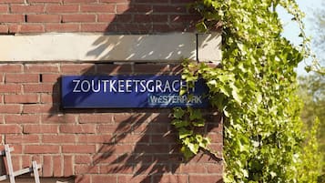 En bygning i mursten med et skilt, der viser 'ZOUTKEETSGRACHT WESTERPARK', og et vindue med en træstige.