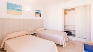A hotel room with two beds, a wardrobe, and a small seating area. - Apartamentos Avenida - MC Apartamentos Ibiza (Ibiza Town)
