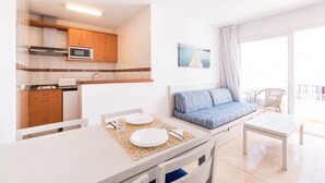 A compact living space with a kitchenette, a dining area, and a seating area with a view. - Apartamentos Avenida - MC Apartamentos Ibiza (Ibiza Town)