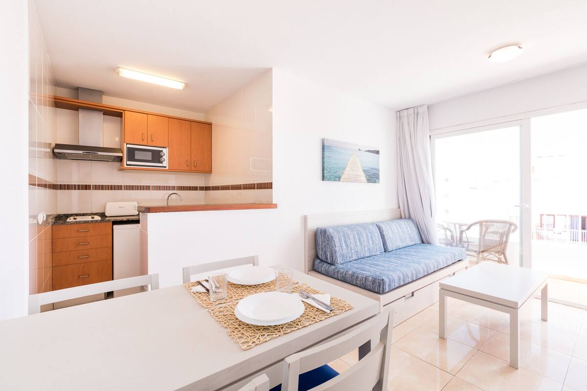 A compact living space with a kitchenette, a dining area, and a seating area with a view.
