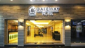 Entrada del The Gateway Hotel con un diseño moderno, que incluye una recepción y un área de estar en su interior.