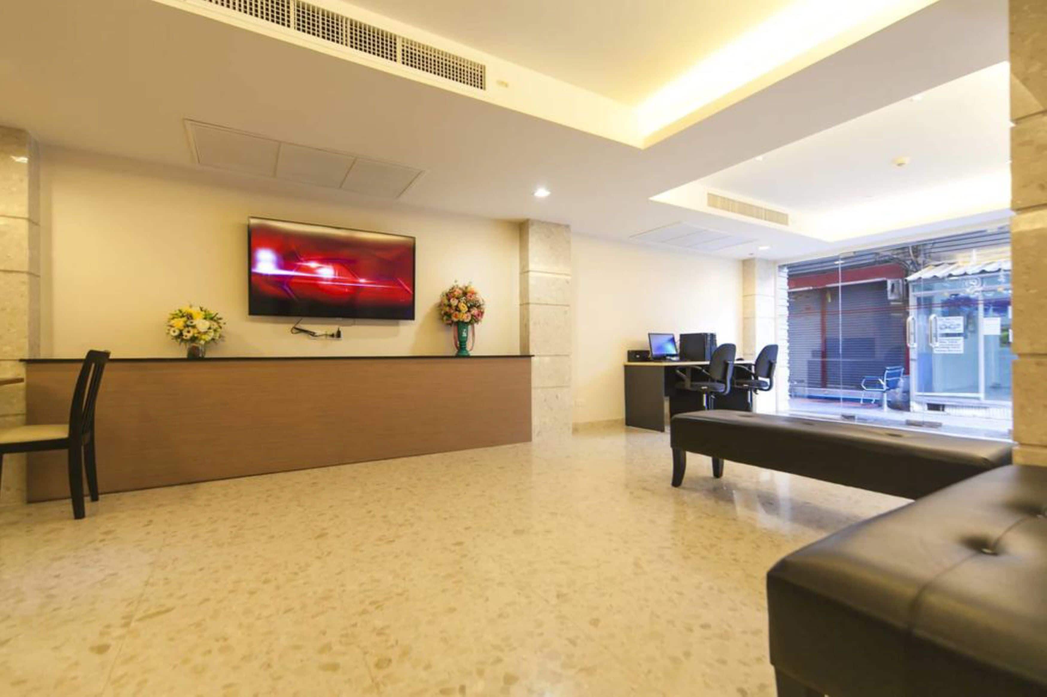 A reception area with a flat-screen TV, a reception desk, a bench, and a window with a view of a closed shop.
