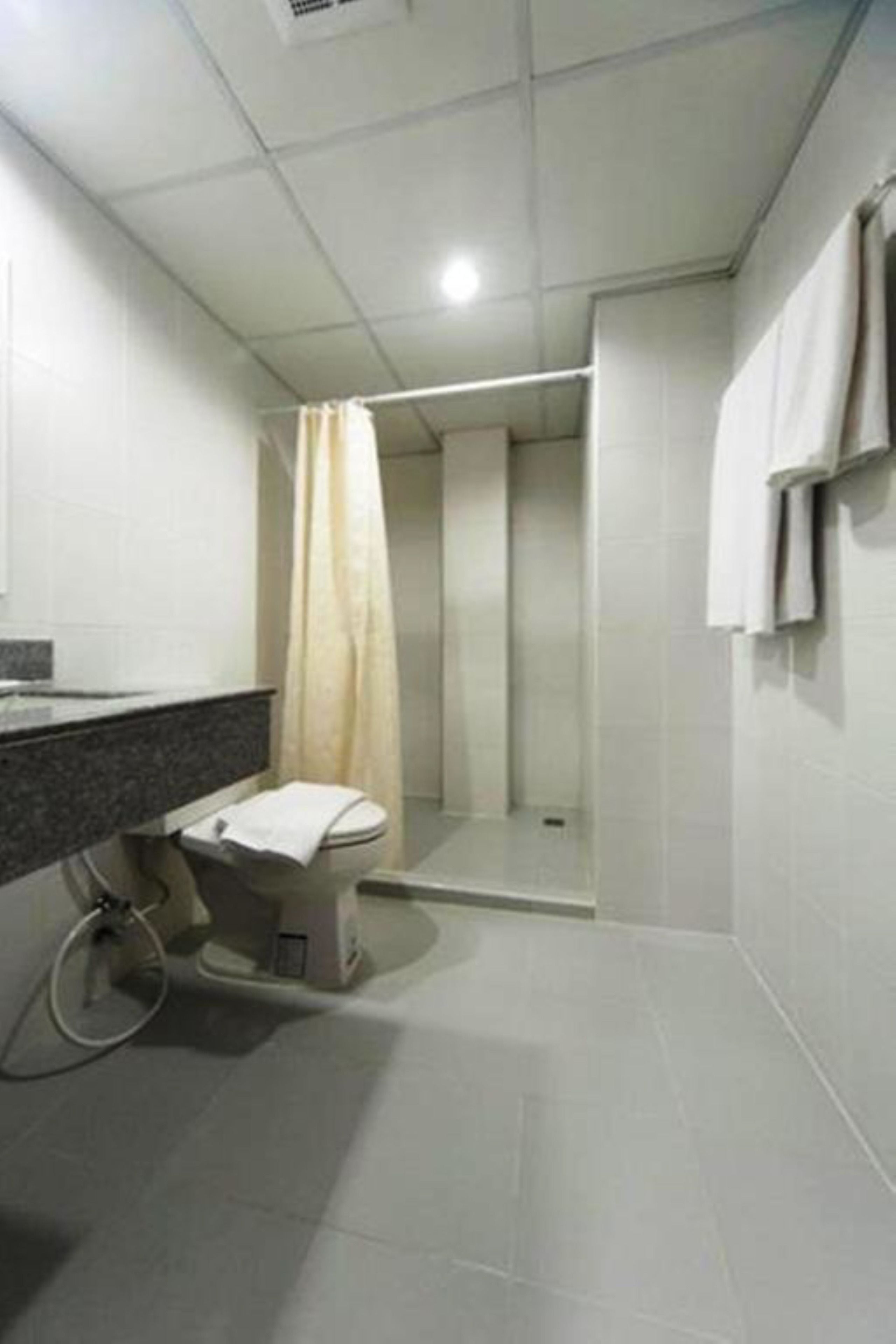 Un baño moderno con inodoro, ducha y un perchero para toallas.