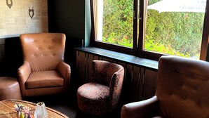 A room with two leather armchairs, a patterned armchair, and a wooden coffee table with decorative items. - Lohmann's Kapeller Hof (Langenfeld)