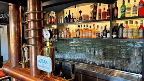A bar area with a copper beer tap, a variety of liquor bottles, and a glassware display. - Lohmann's Kapeller Hof (Langenfeld)