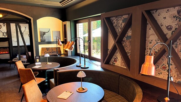 A cozy restaurant interior with round tables, cushioned seating, and decorative wall panels. - Lohmann's Kapeller Hof (Langenfeld)