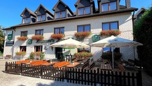 A hotel with multiple windows, outdoor seating, and flower boxes. - Lohmann's Kapeller Hof (Langenfeld)