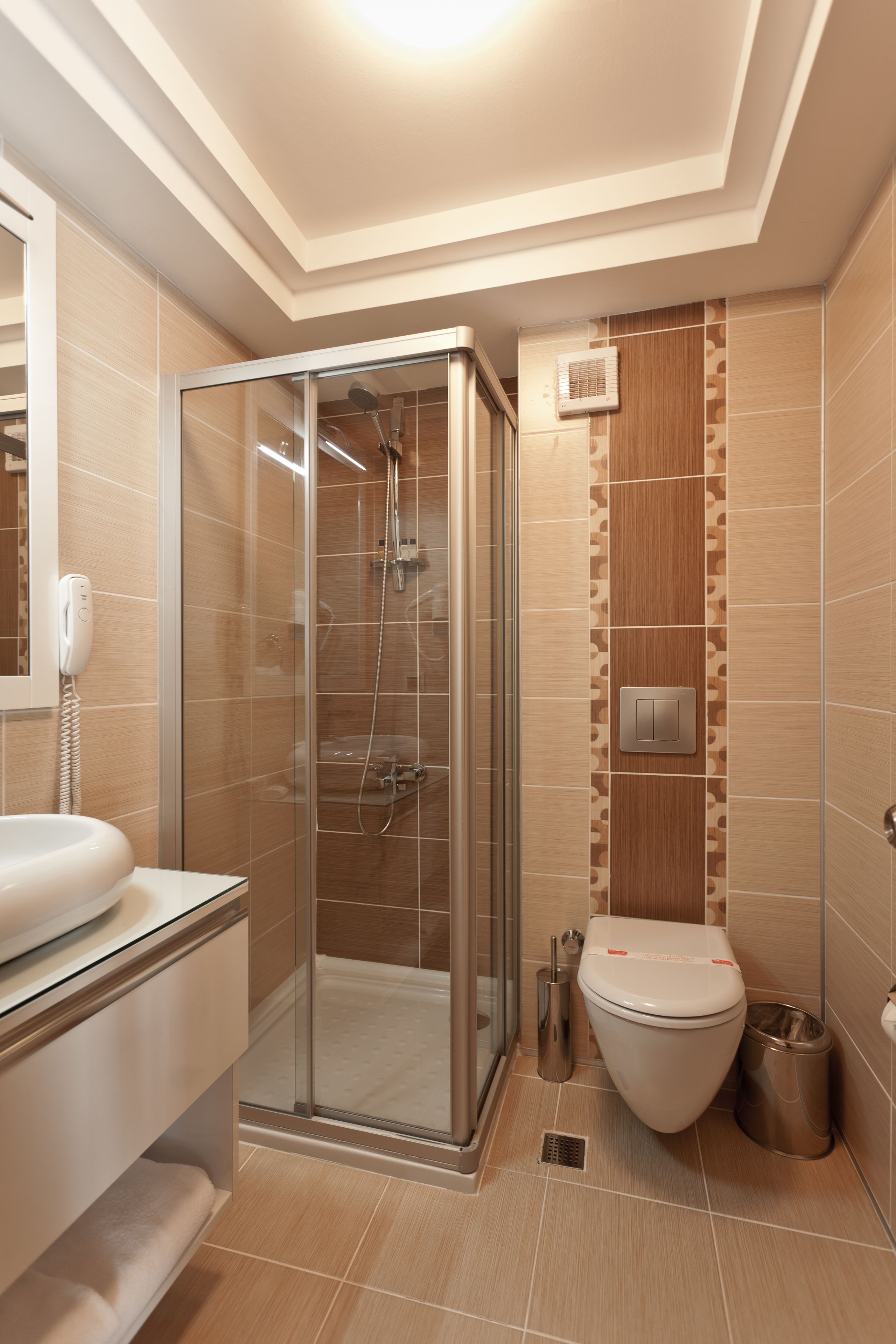 A modern bathroom with a glass-enclosed shower, a toilet, and a sink.