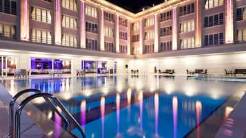 Relax by the pool, surrounded by a classic building with a seating area and tables.