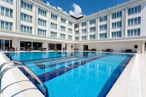 Ein großes Hallenbad mit Fliesenboden und einem weißen Gebäude mit zahlreichen Fenstern im Hintergrund.