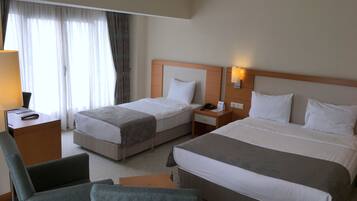 Habitación de hotel con dos camas, un escritorio, una silla y una lámpara.
