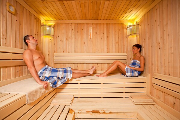 A sauna with wooden benches and benches, a clock on the wall, and a towel rack.