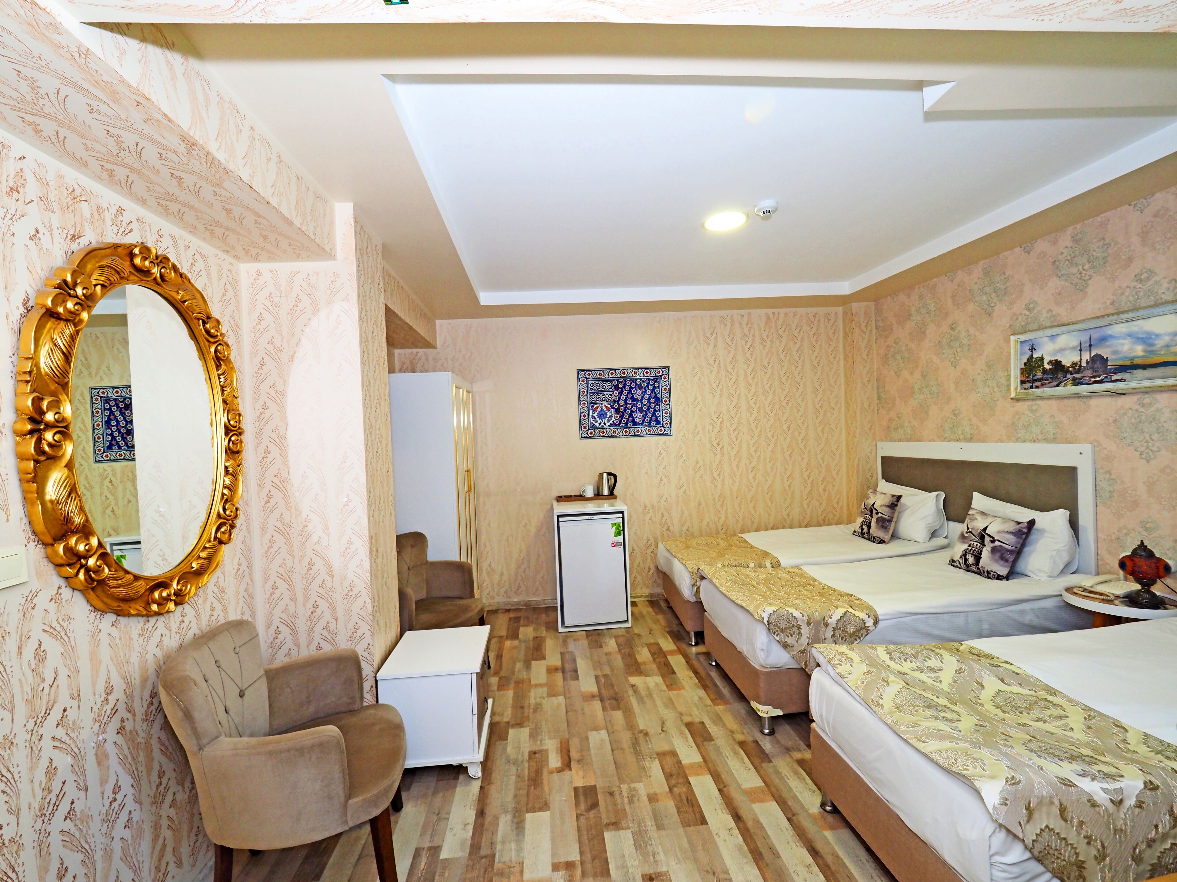 Una habitación de hotel con dos camas, un escritorio, una silla, un refrigerador y un espejo.