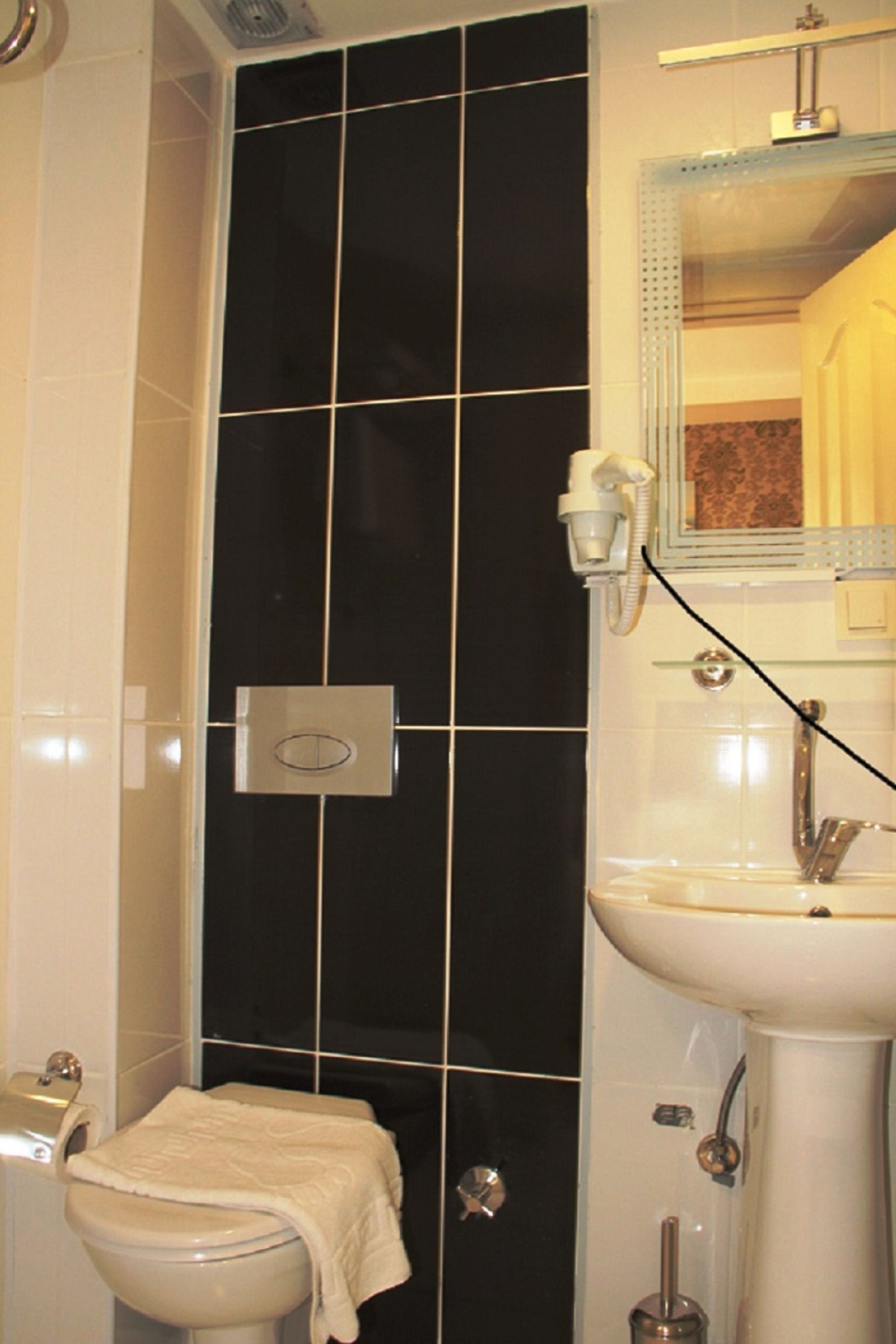 A bathroom with a toilet, sink, and mirror.