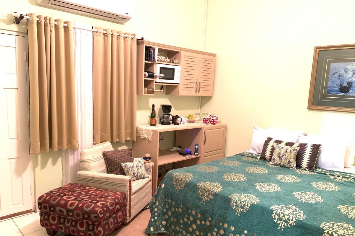 A hotel room with a bed, a sofa, a small table, a microwave, a coffee maker, and a framed picture on the wall.