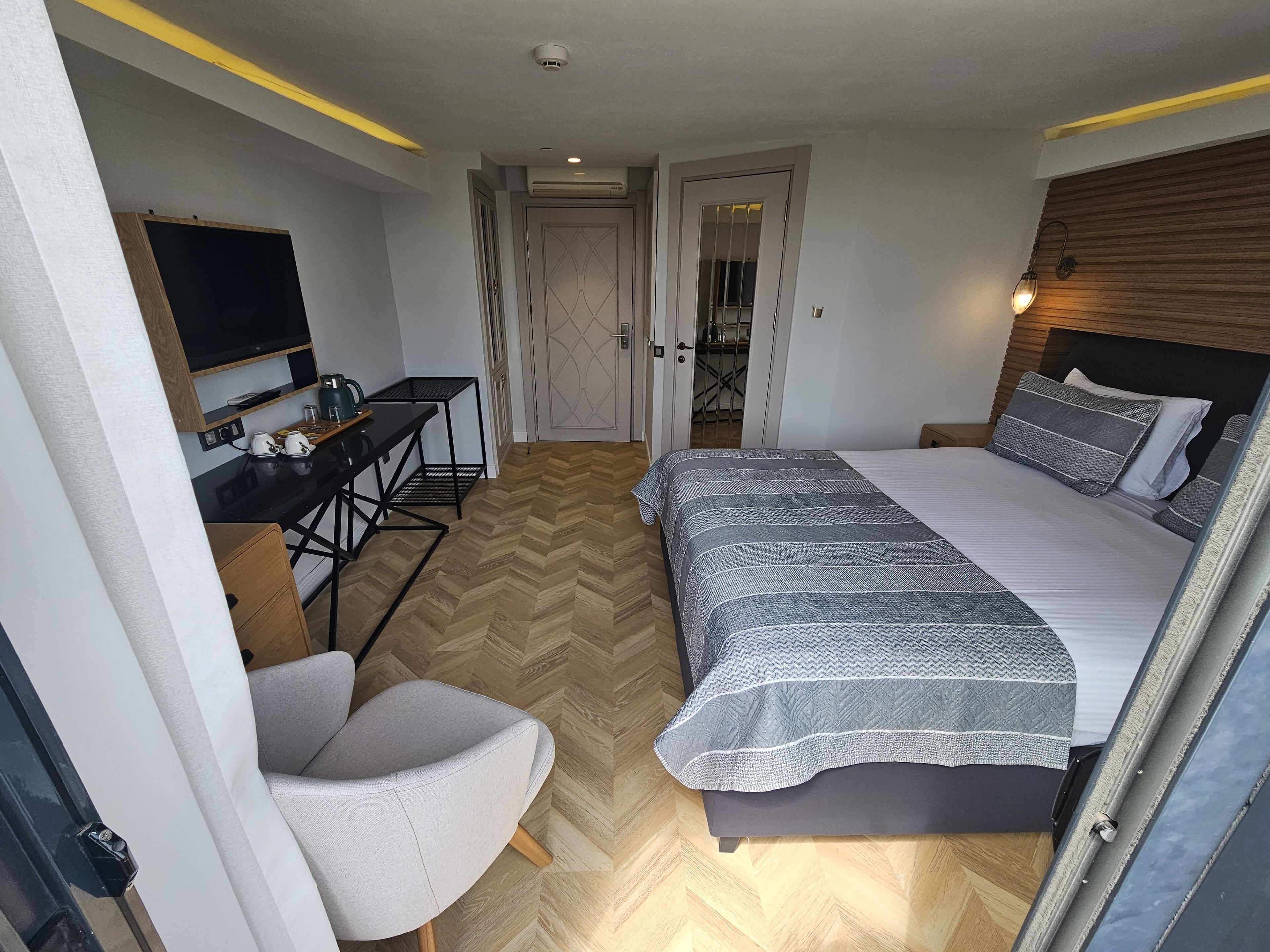 A compact bedroom with a bed, a desk, a chair, and a television.
